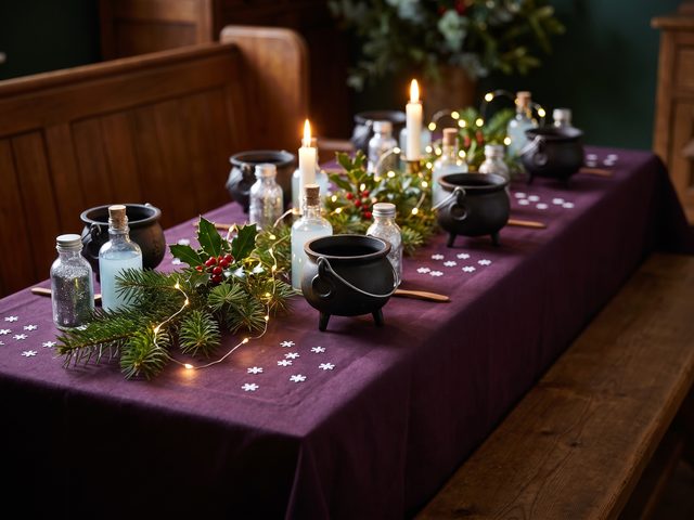 Cauldrons and glitter potion bottles among pine, holly and fairy lights
