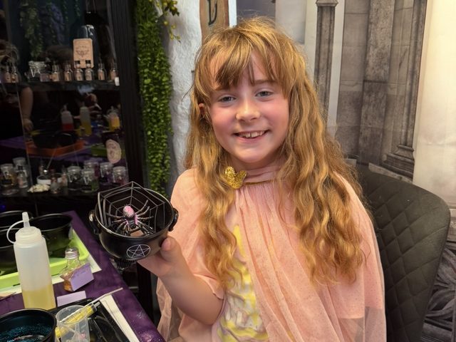 A girl in a pink fairy cloak holding her finished fairy potion