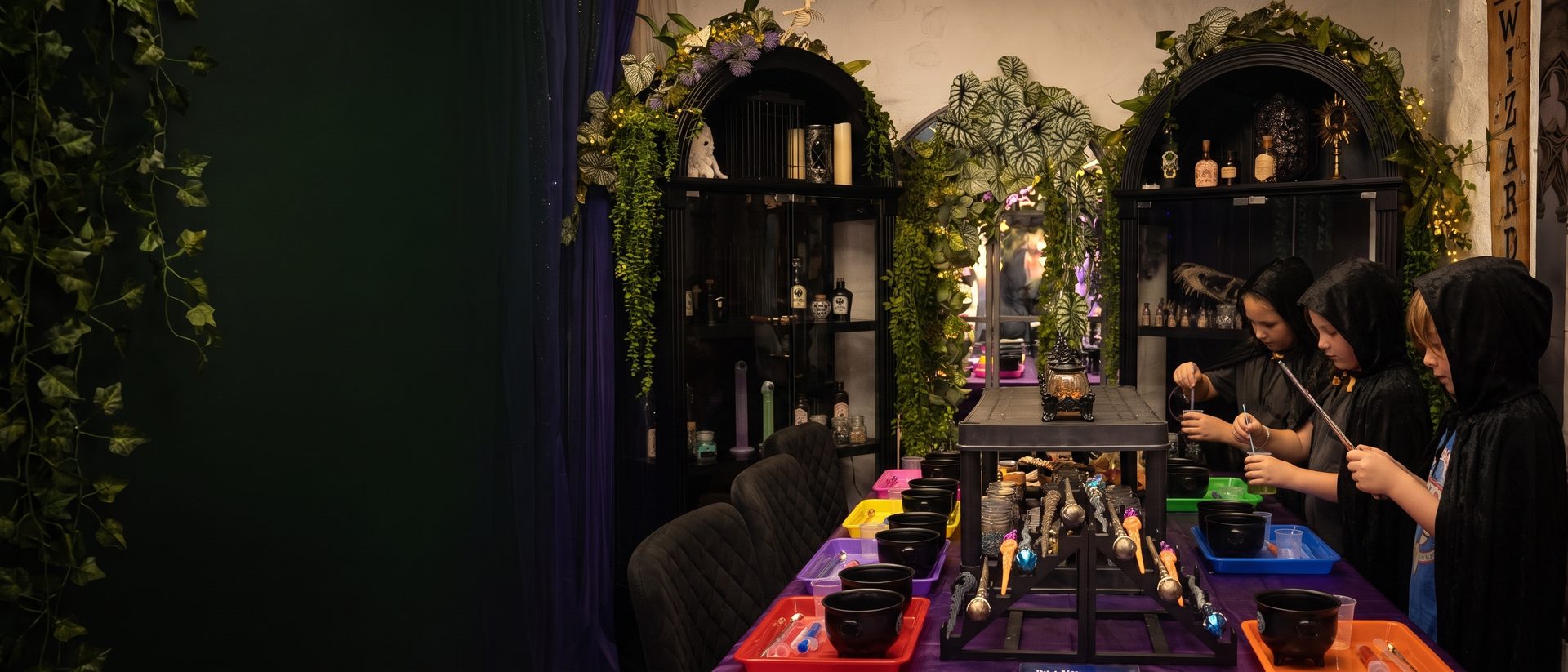 The potion bench set up for a Wizard School party, with cauldrons, wands and shelves of apothecary bottles